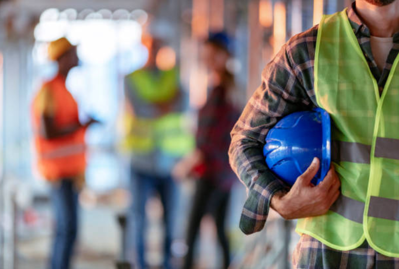 Foundation Repair Contractor holding a blue hard hat at a construction site with a team in the background