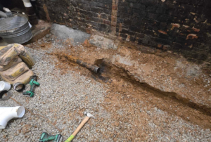 Foundation trench dug along basement wall to address wet basement with drainage piping