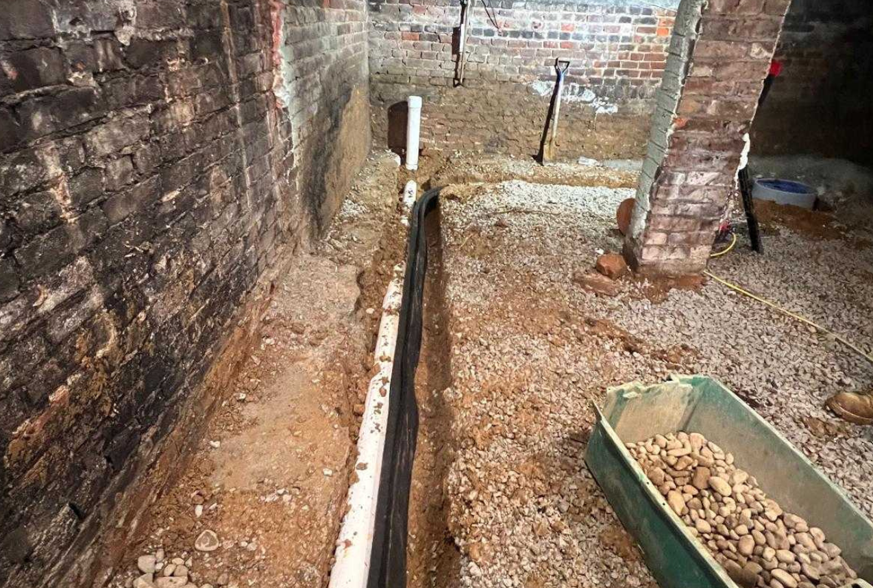 Interior basement waterproofing system with trench drain installation to prevent a wet basement