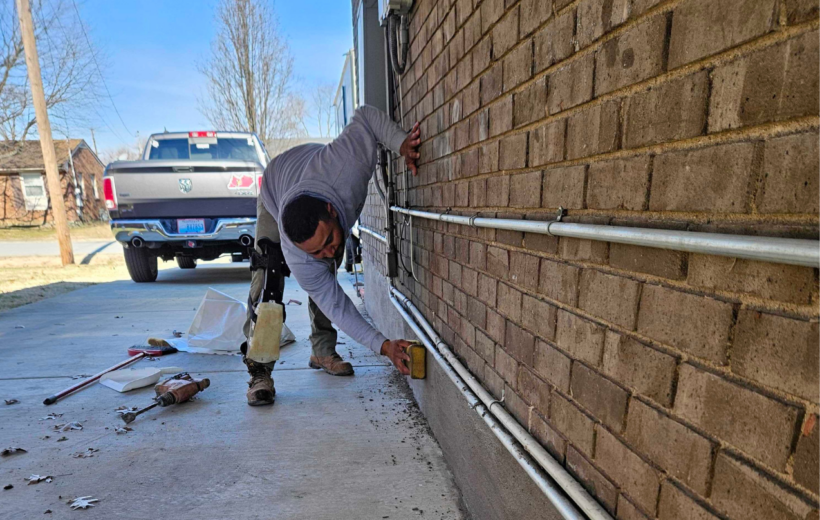 Technician repairing foundation cracks on exterior brick wall of a home in Kentucky