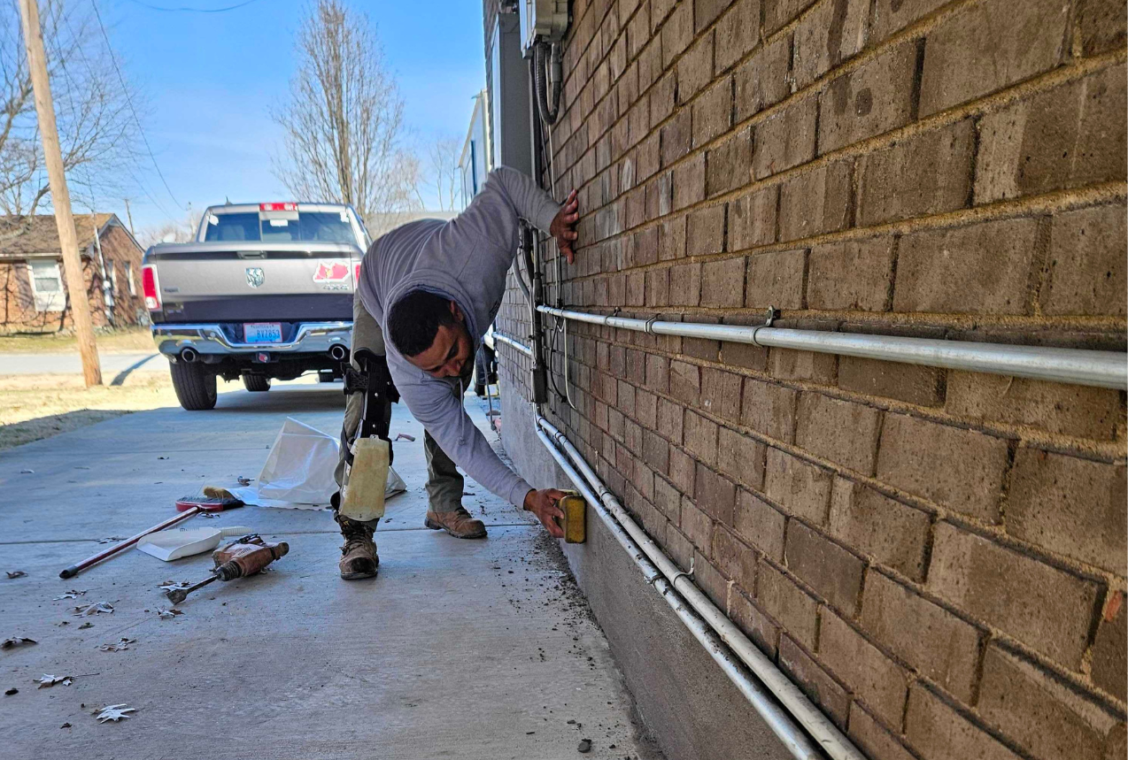 Technician repairing foundation cracks on exterior brick wall of a home in Kentucky