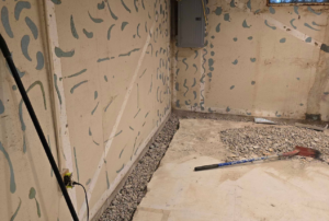 Interior basement prep work with exposed wall and drainage trench to fix bowing walls