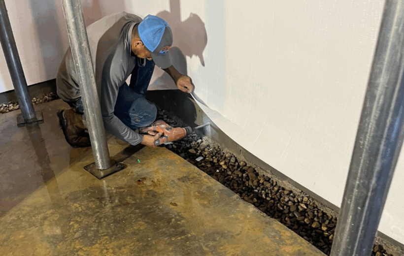 A KCS crew member installing a foundation repair system in a basement
